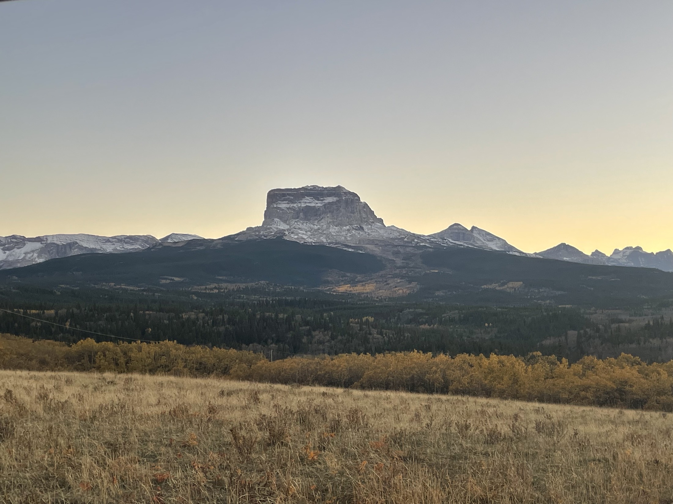Chief Mountain at sunrise above a golden prairie
